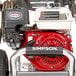 A Simpson gas powered pressure washer with a red hose.