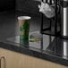 A coffee cup sitting on an ES Robbins clear vinyl countertop mat on a counter.