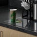 A coffee cup sits on an ES Robbins clear vinyl countertop mat on a counter.