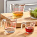 An Anchor Hocking glass measuring cup with yellow liquid inside on a kitchen counter.