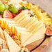 A plate of John F. Martin Muenster cheese and fruit on a wooden board.