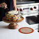 A woman frosting a round cake on a plate.