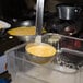 A person using a Vollrath Jacob's Pride ladle to serve food from a container.