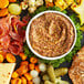 A plate of food with a variety of snacks including Savor Imports French Whole Grain Mustard.