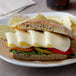 A sandwich with cheese, tomatoes, and vegetables on a plate.