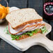 A Carolina Turkey Deluxe sandwich with meat and vegetables on a cutting board.