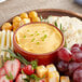 A platter with cheese spread, fruit, and crackers on a table.