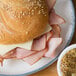 A sandwich with ham and Land O Lakes White American Cheese on a plate.