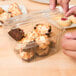 A hand putting a piece of chocolate into a Genpak clear plastic deli container.