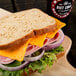 A sandwich with Yancey's Fancy Buffalo Wing Cheddar Cheese, meat, and cheese on a cutting board.