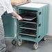 A person putting trays in a Cambro mobile cart.