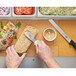 A person's hands cutting a sandwich on an Epicurean PuzzleBoard.