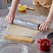 A person rolling out dough on a table with a Fox Run marble rolling pin.