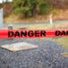 A roll of red Cordova danger tape with black text on the ground.