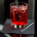 A Libbey Lexington rocks glass with red liquid, ice, and a straw.