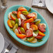 A plate of tomatoes and mozzarella on a blue Tuxton Concentrix oval platter.