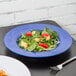 A Carlisle Ocean Blue melamine chef salad bowl with a salad and a silver fork on a table.