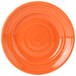 A close-up of a Tuxton Concentrix papaya orange plate with a spiral pattern.
