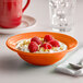 A Tuxton papaya grapefruit bowl filled with raspberries.