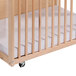A wooden crib with a Whitney Brothers white fitted sheet on the mattress.