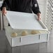 A person holding a white Baker's Mark dough proofing box lid with dough inside.