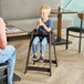 A brown designer high chair for children, shown in use at a restaurant table.