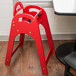 A red Koala Kare high chair sits in front of a table.