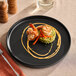 A Tuxton Zion matte black china plate with food on it.