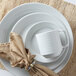 A Tuxton Pacifica bright white embossed china plate with a brown napkin on top.