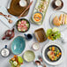 A table with Tuxton Zion Matte Black bread and butter plates and bowls of food on it.