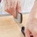 A hand using a Victorinox handheld knife sharpener on a knife blade.