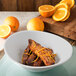 A Carlisle Griege melamine bowl filled with food next to orange slices.