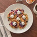 An Acopa ivory stoneware plate with waffles, blueberries, and whipped cream.