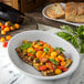 A Carlisle Griege Melamine pasta bowl filled with tomatoes and eggplant on a table.