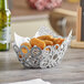 An American Metalcraft silver oval basket filled with fried food on a table.