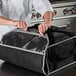 A person opening a black Vollrath insulated pizza delivery bag.