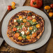 A pizza with tomatoes and spinach on a Carlisle Ridge melamine plate.