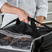 A chef holding a black Vollrath 5-Series insulated pizza delivery bag with a black strap.