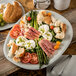 A Carlisle cement melamine oblong platter with asparagus, tomatoes, and bread on a table.