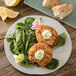 A Carlisle cement melamine plate with food including crab cakes and bread.