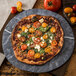 A pizza with tomatoes, cheese, and basil on a Carlisle soapstone plate.