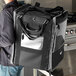 A person carrying a black and white Vollrath 3-Series insulated tower bag on their shoulder.