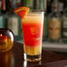 A Libbey Gallery beverage glass with a drink and a slice of orange on a table.