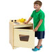 A boy in a green shirt standing next to a Whitney Brothers natural wood stove for children.