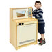 A young boy playing with a Whitney Brothers natural wood toy microwave oven.