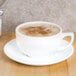 A white CAC porcelain cappuccino cup on a saucer with foamy brown coffee.