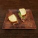 A sandwich cut in half on an Elite Global Solutions checkered bamboo and melamine plate.