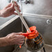 A person using a white tube brush to clean a coffee decanter.