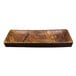 A rectangular wood grain melamine serving platter with a rough edge.