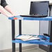 A woman using a laptop on a blue Luxor utility cart shelf.